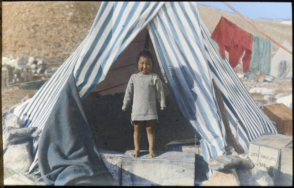 Eskimo boy at entrance of tent