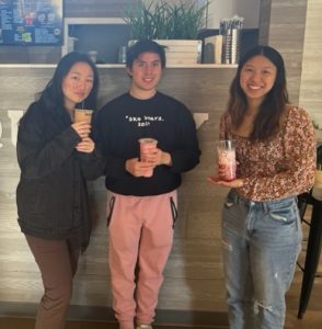 three undergraduates indoor standing with boba tea